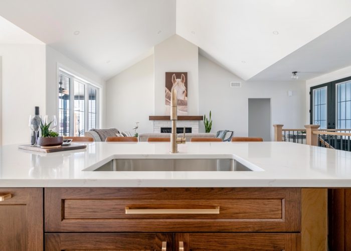 A sink in kitchen island overlooked a vaulted living room with gas fireplace.