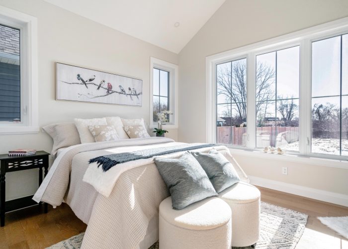 A master bedroom with large windows and vaulted ceiling.