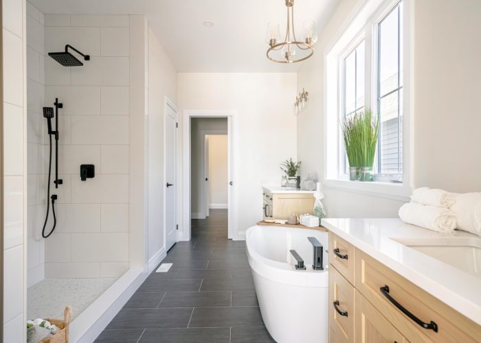 A bathroom with soaker tub, double wooden vanities and custom tiled shower.