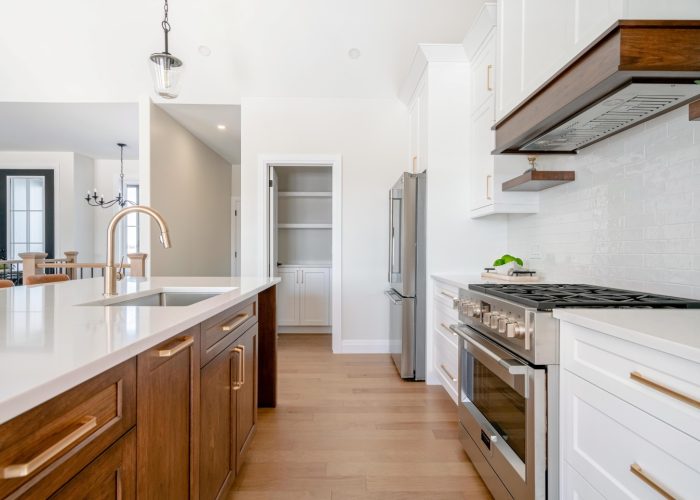 A stained wood island a white cabinetry custom kitchen with a walk-in pantry and luxurious appliances.