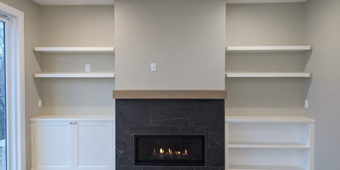 A gas fireplace with wooden mantle and built-in cabinetry on either side.