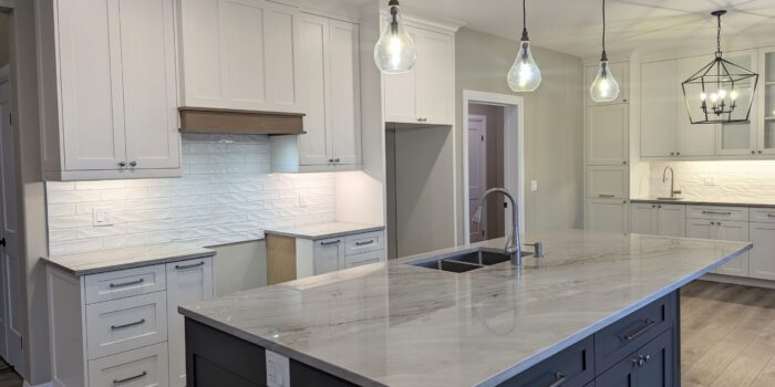 A white and grey kitchen with cabinetry to the ceiling and beautiful quartzite countertops.