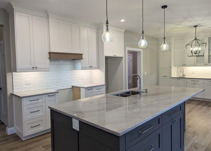 A white and grey kitchen with cabinetry to the ceiling and beautiful quartzite countertops.